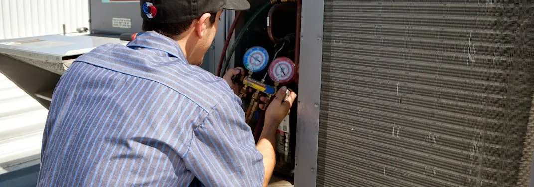 HVAC technician servicing a condenser unit in Manvel